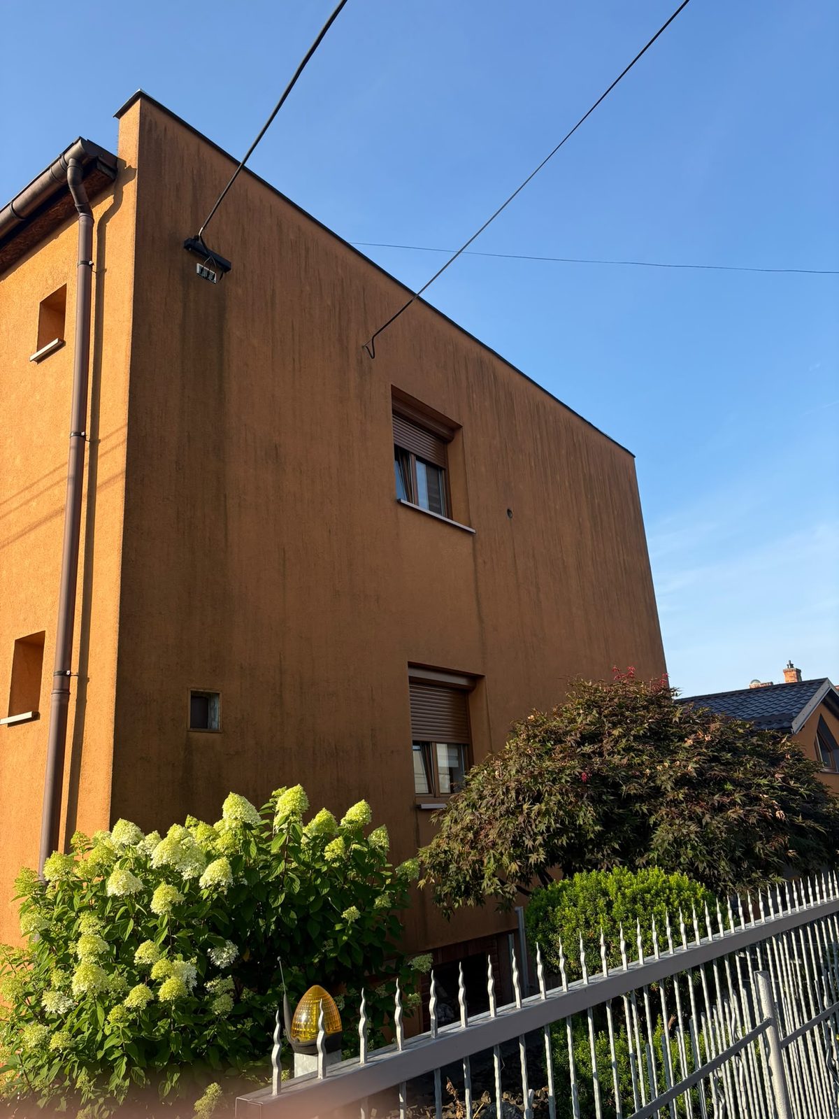 Zašlá oranžová fasáda se stopami po stékající vodě před čištěním