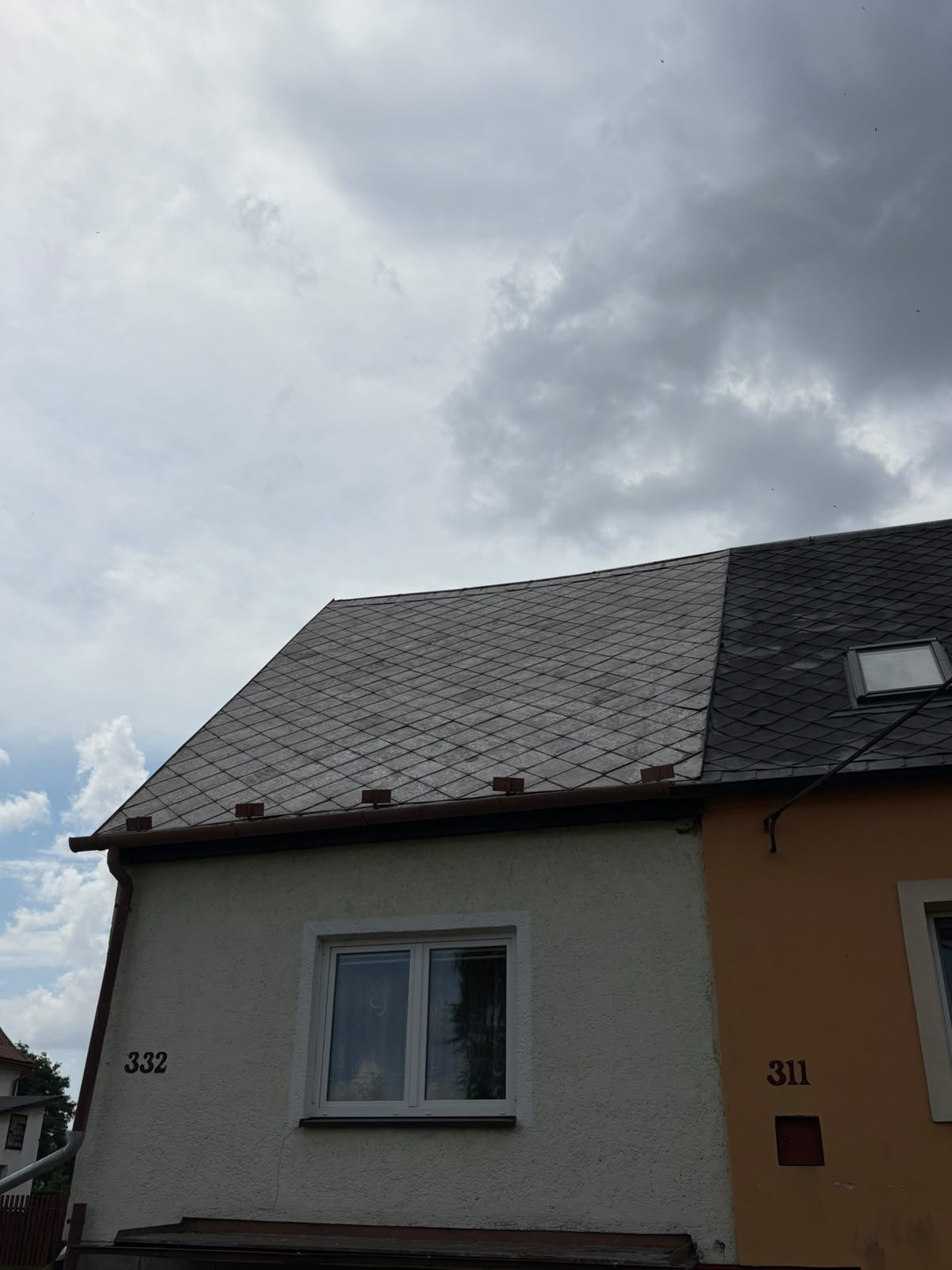 Střecha rozdělená na polovinu: vlevo neumytá krytina s lišejníkem, vpravo tmavá umytá část